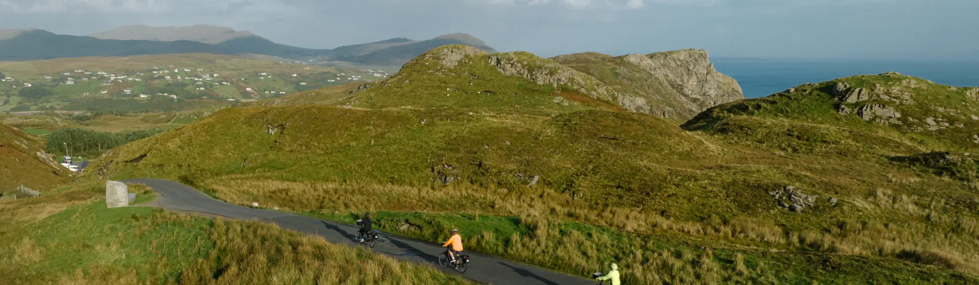 A scenic aerial view of cyclists riding along a narrow