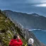 Hikers overlooking the rugged Sliabh Liag cliff with green vegetation on a cloudy day.